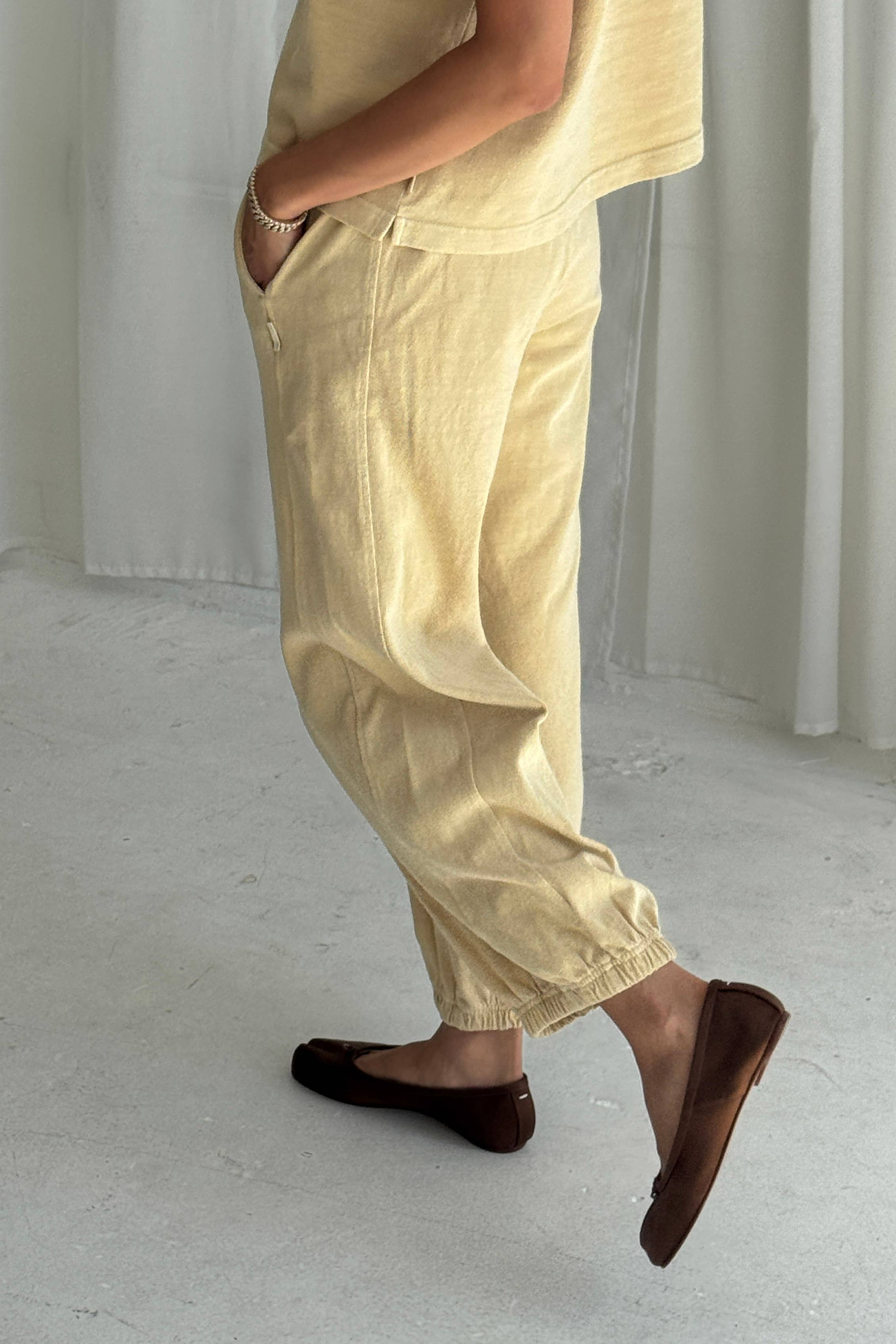Person wearing yellow pants and brown shoes in a minimalistic setting