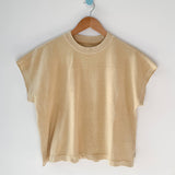 Yellow t-shirt on a wooden hanger against a white wall