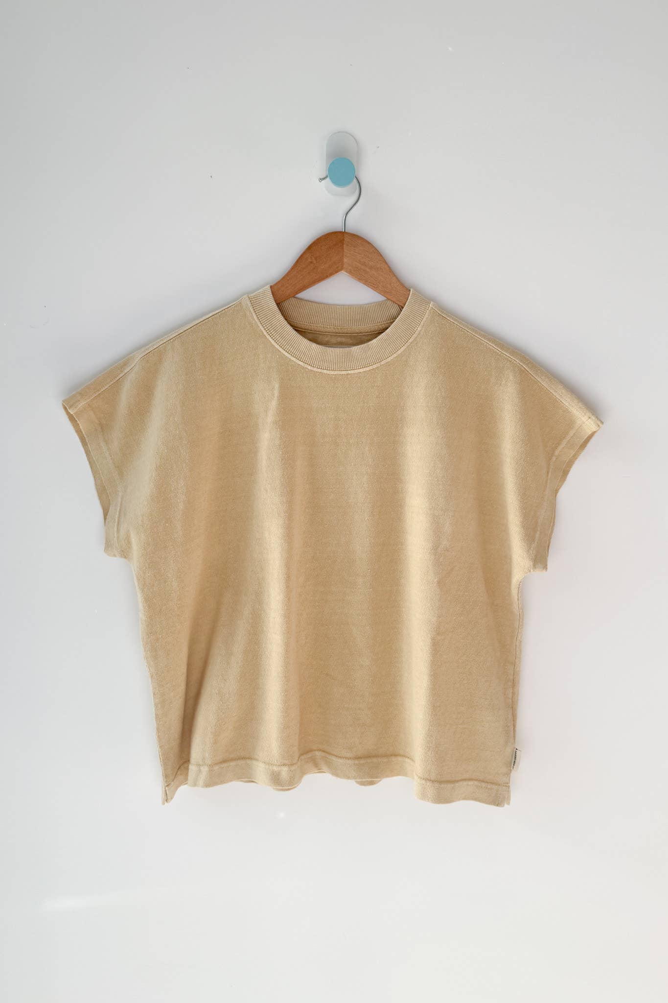 Yellow t-shirt on a wooden hanger against a white wall