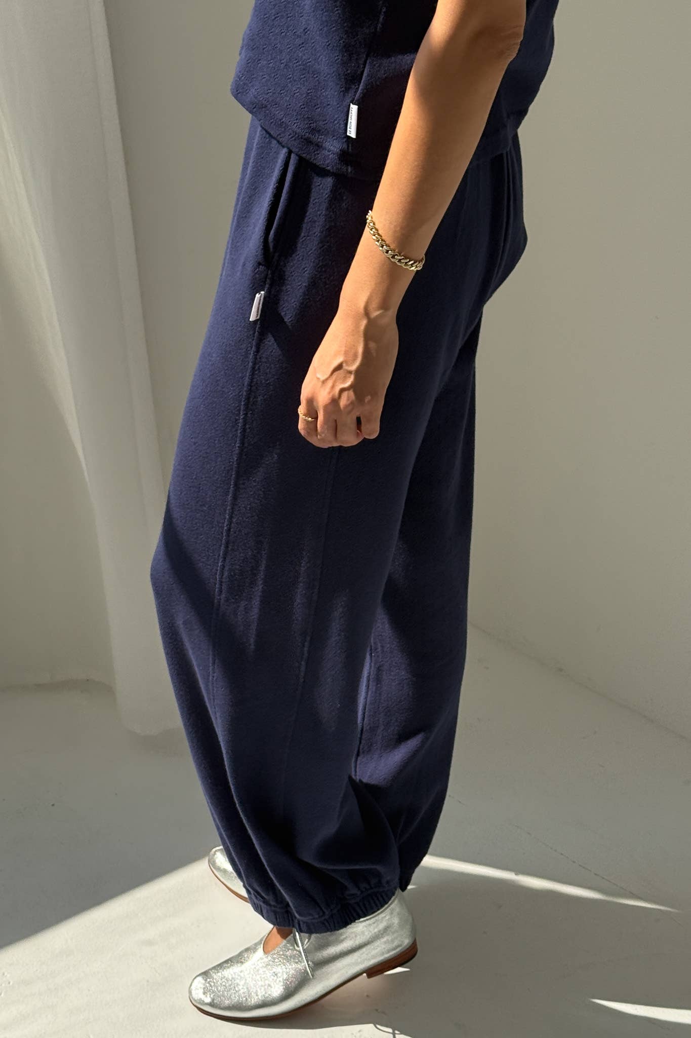 Person wearing navy blue wide-leg pants with a white background