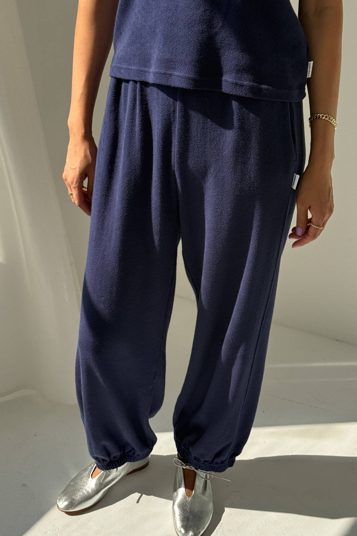 Person wearing navy blue pants and silver shoes on a light background