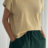 Person wearing a yellow t-shirt and green pants against a white background
