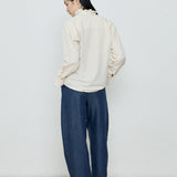 Person wearing a white blouse and blue pants against a plain background