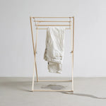 Gold clothing rack with a white garment on a plain background