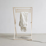 Gold clothing rack with a white garment on a plain background