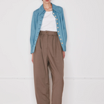 Person wearing a blue denim jacket, white shirt, and brown pants on a white background