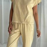 Person wearing a yellow outfit against a white curtain background