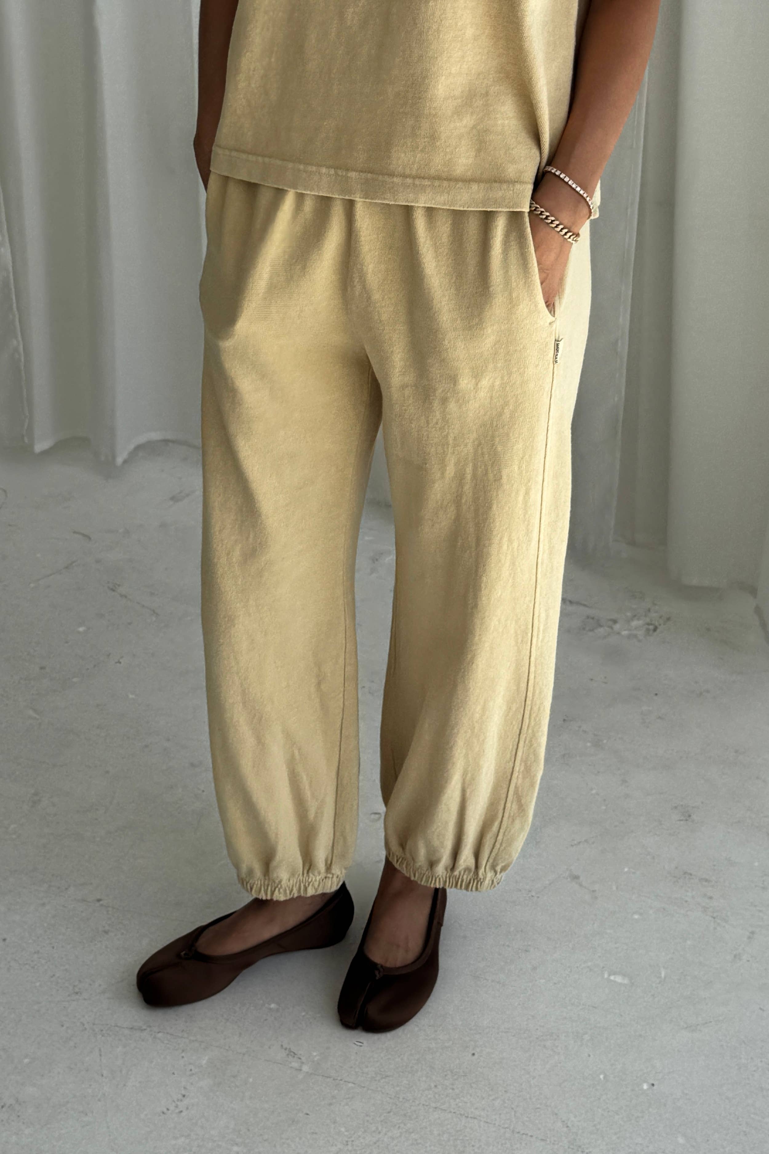 Person wearing yellow pants and a matching top on a plain background