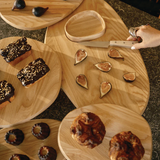Assorted wooden cutting board with figs and pastries on a dark surface