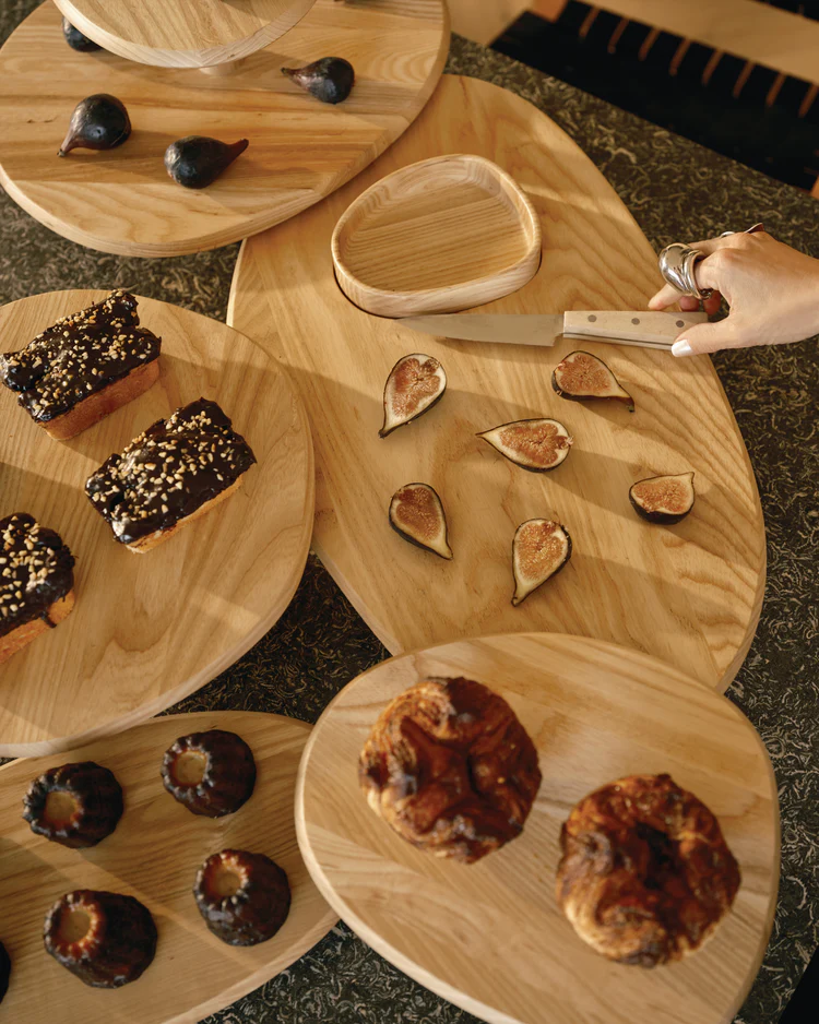 Assorted wooden cutting board with figs and pastries on a dark surface