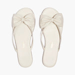 Pair of white sandals with bow details on a white background