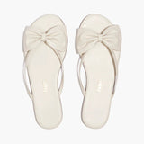 Pair of white sandals with bow details on a white background