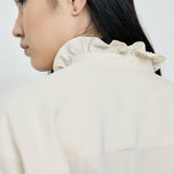 Person wearing a light-colored shirt with a plain background