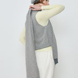Person wearing a striped sweater, white pants, and a gray beanie on a plain background