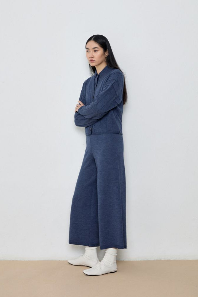 Person wearing a blue outfit standing against a white wall