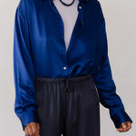 Person wearing a blue shirt and dark pants against a white background