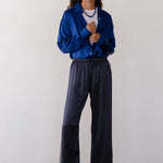 Person wearing a blue shirt and dark pants against a white background