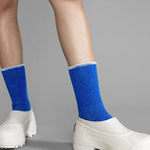 Blue socks worn with white shoes on a gray background