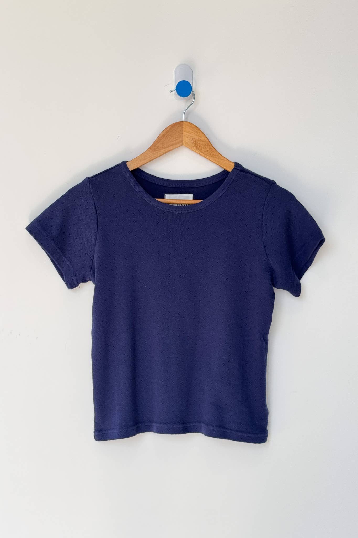 Navy blue t-shirt on a wooden hanger against a white background