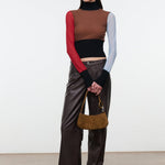 Model wearing brown leather trousers and holding the STAUD Ollie Bag in Cigar suede