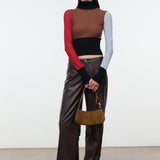 Model wearing brown leather trousers and holding the STAUD Ollie Bag in Cigar suede