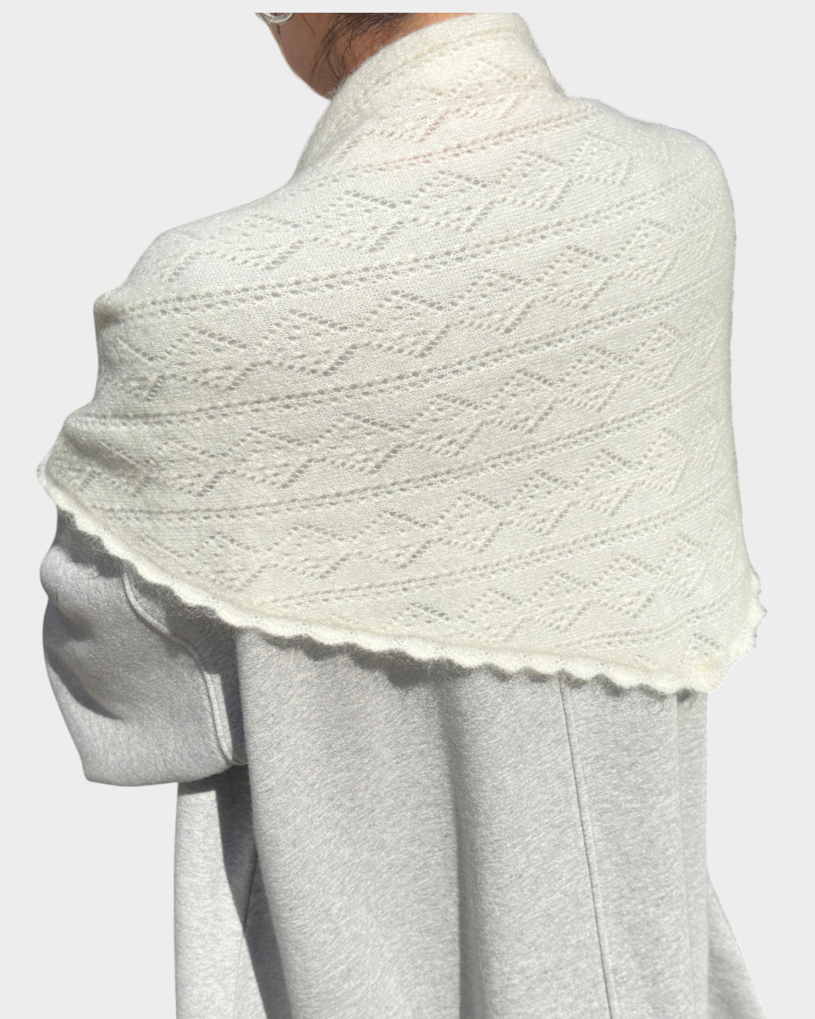 JONES + CO pearl mohair pointelle shawl with delicate scalloped edges draped over shoulders outdoors