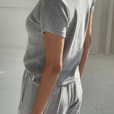 Person wearing a gray outfit in a minimal white room