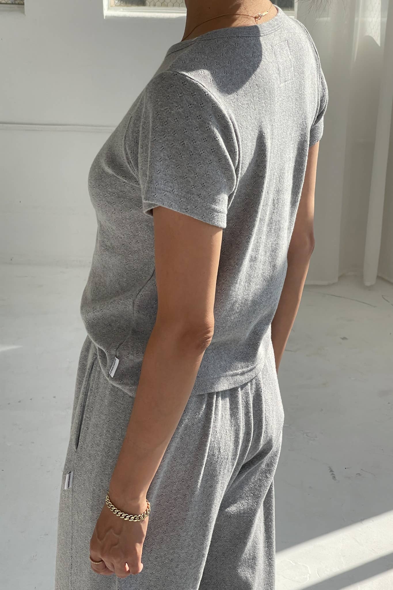 Person wearing a gray outfit in a minimal white room