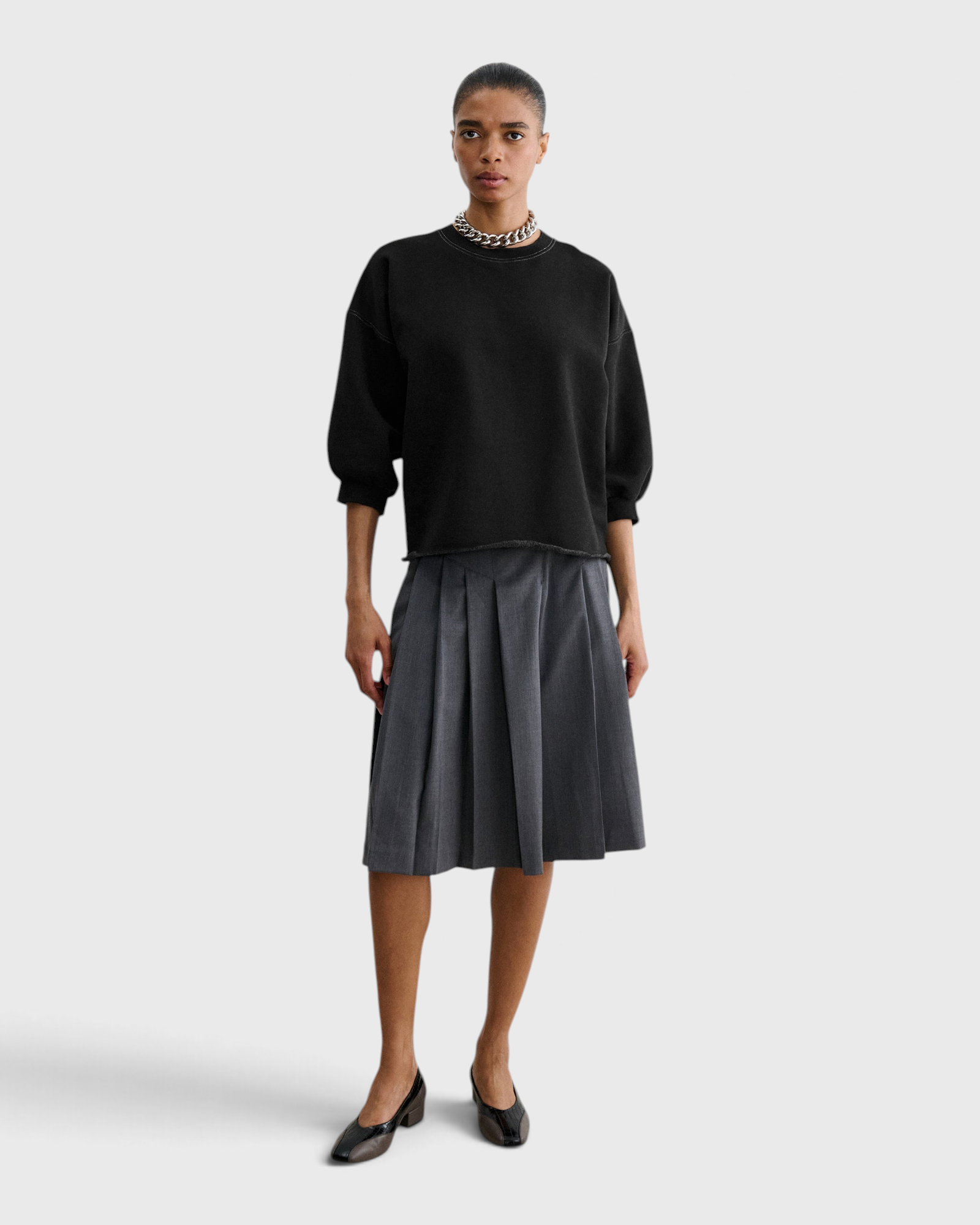 JONES + CO Rachel Comey Fond Sweatshirt in charcoal, full-length front view styled with a pleated skirt