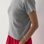Person wearing a gray t-shirt and red pants on a plain background