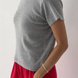 Person wearing a gray t-shirt and red pants on a plain background