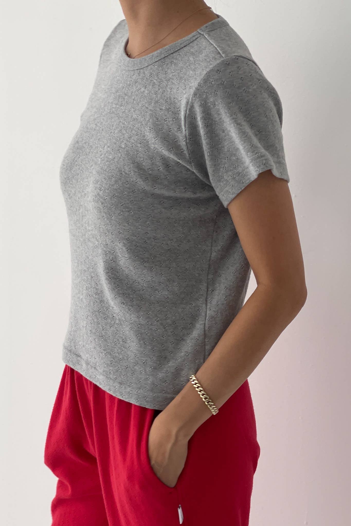 Person wearing a gray t-shirt and red pants on a plain background