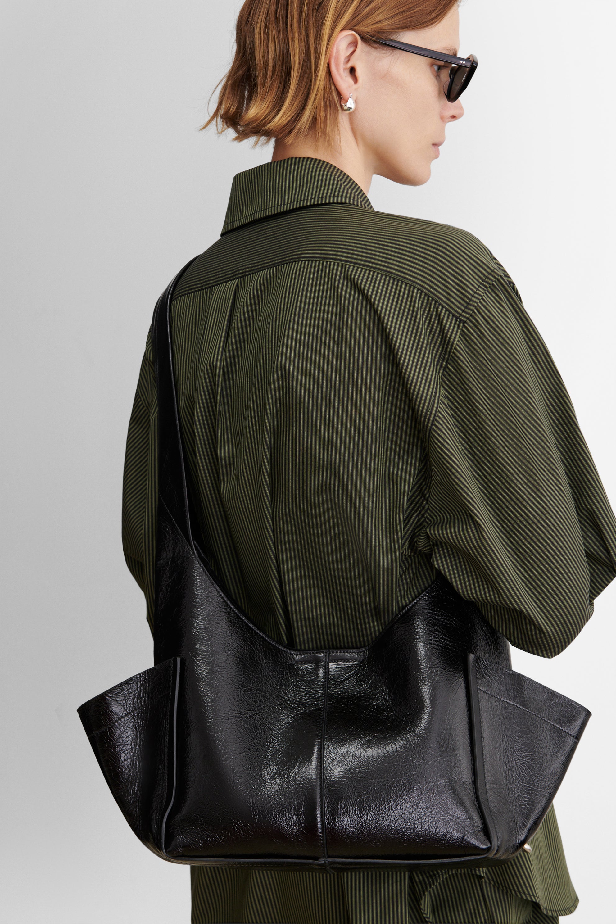Model carrying the RACHEL COMEY Tool Bag in black leather over the shoulder.