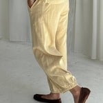 Person wearing yellow pants and brown shoes in a minimalistic setting