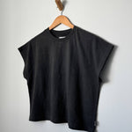 Black sleeveless top on a wooden hanger against a plain background
