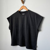 Black sleeveless top on a wooden hanger against a plain background
