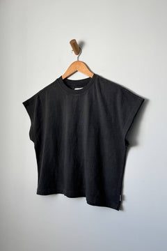 Black sleeveless top on a wooden hanger against a plain background