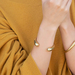 Person wearing a gold bracelet on a mustard yellow sweater