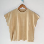 Yellow t-shirt on a wooden hanger against a white wall