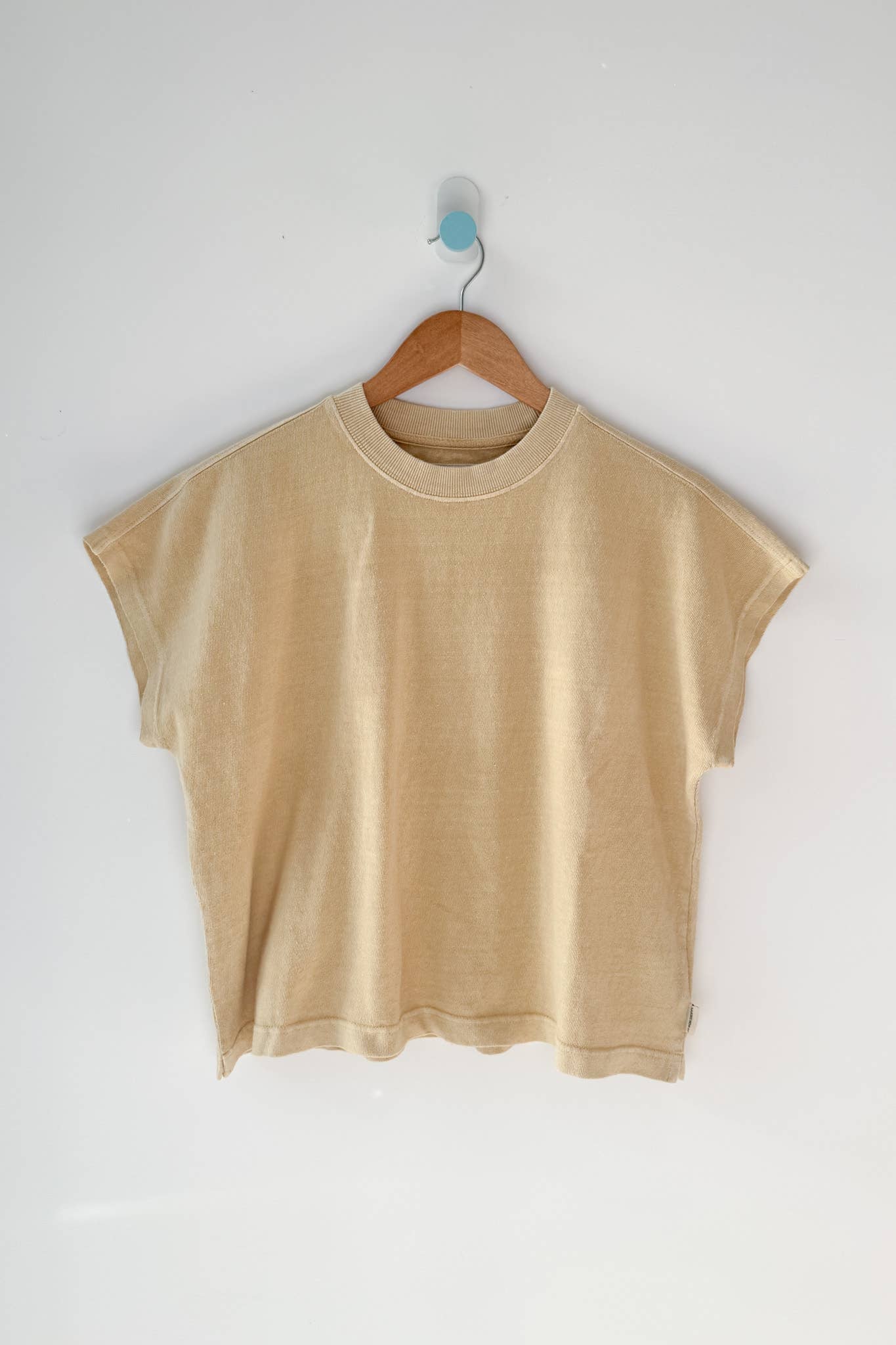 Yellow t-shirt on a wooden hanger against a white wall