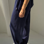 Person wearing navy blue wide-leg pants with a white background