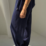Person wearing navy blue wide-leg pants with a white background