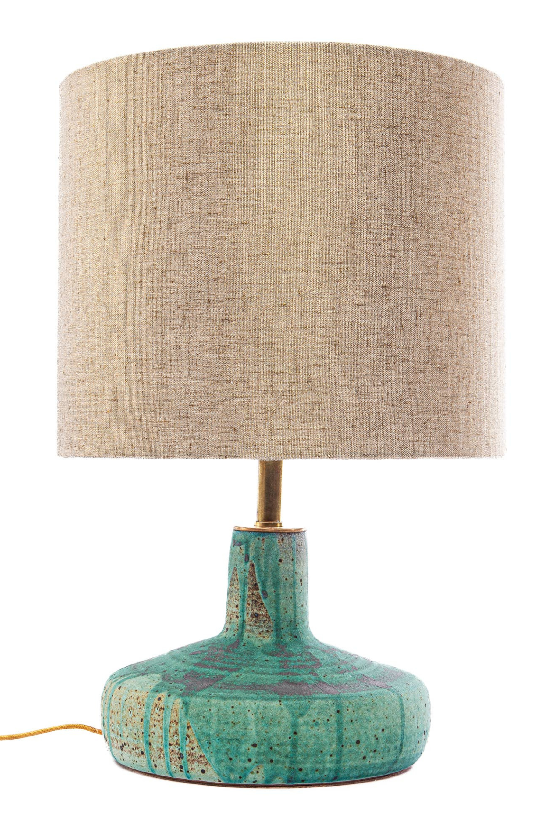 Table lamp with textured green base and beige fabric shade on a white background