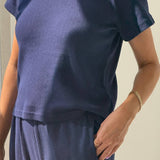 Person wearing a navy blue outfit with a plain background