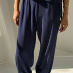 Person wearing navy blue pants and silver shoes on a light background