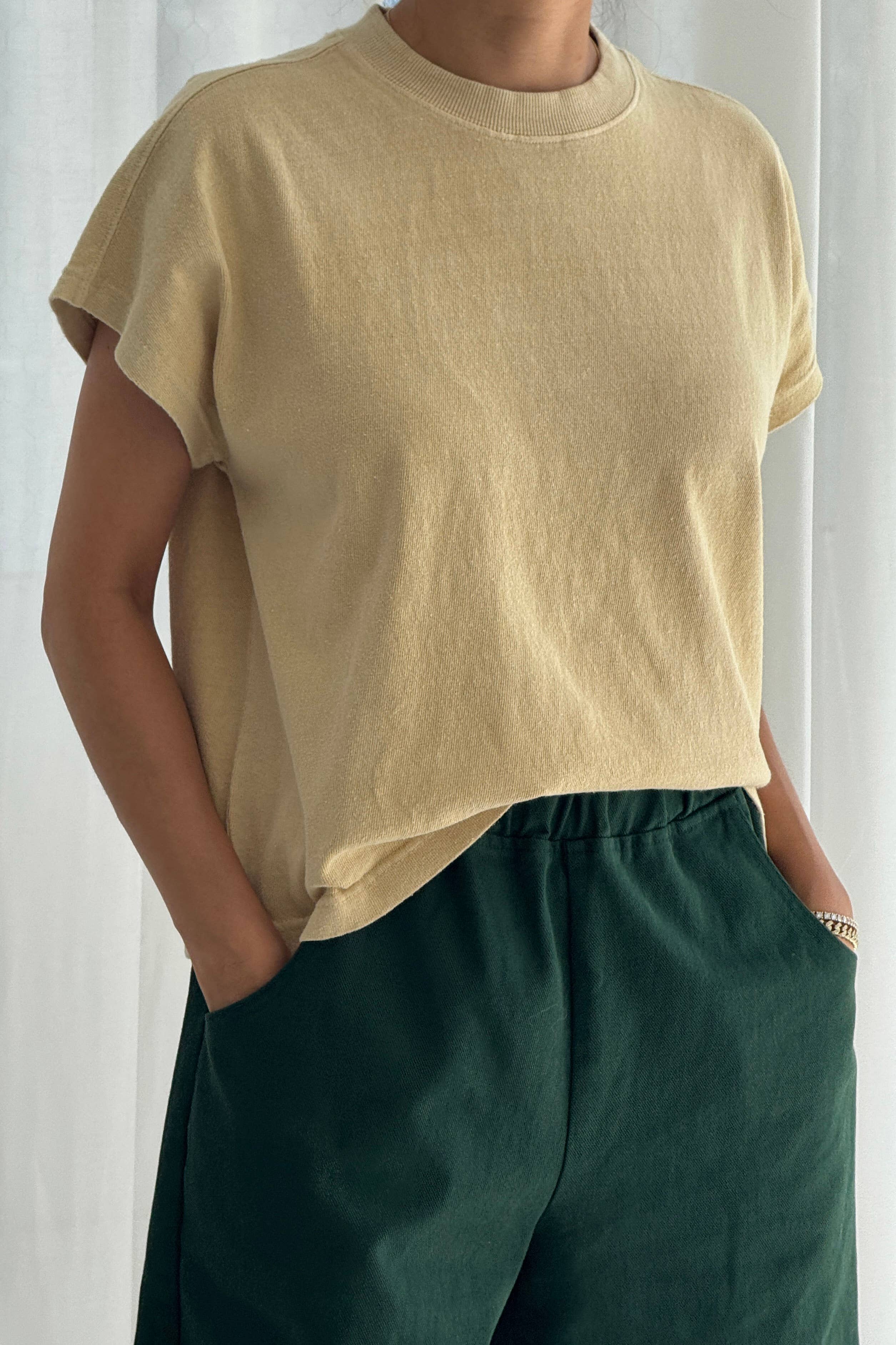 Person wearing a yellow t-shirt and green pants against a white background
