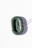 emerald stone catch all tray with a silver necklace laying across, white background