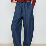 Person wearing a red ribbed sweater and blue wide-leg pants on a plain background