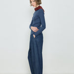 Woman wearing a blue ribbed sweater and dark blue wide-leg pants against a white background