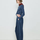 Woman wearing a blue ribbed sweater and dark blue wide-leg pants against a white background